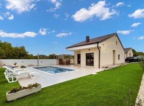 A modern house with a swimming pool, a patio with chairs, and a well-maintained lawn. - Villa Shaula 1 (Bilice)