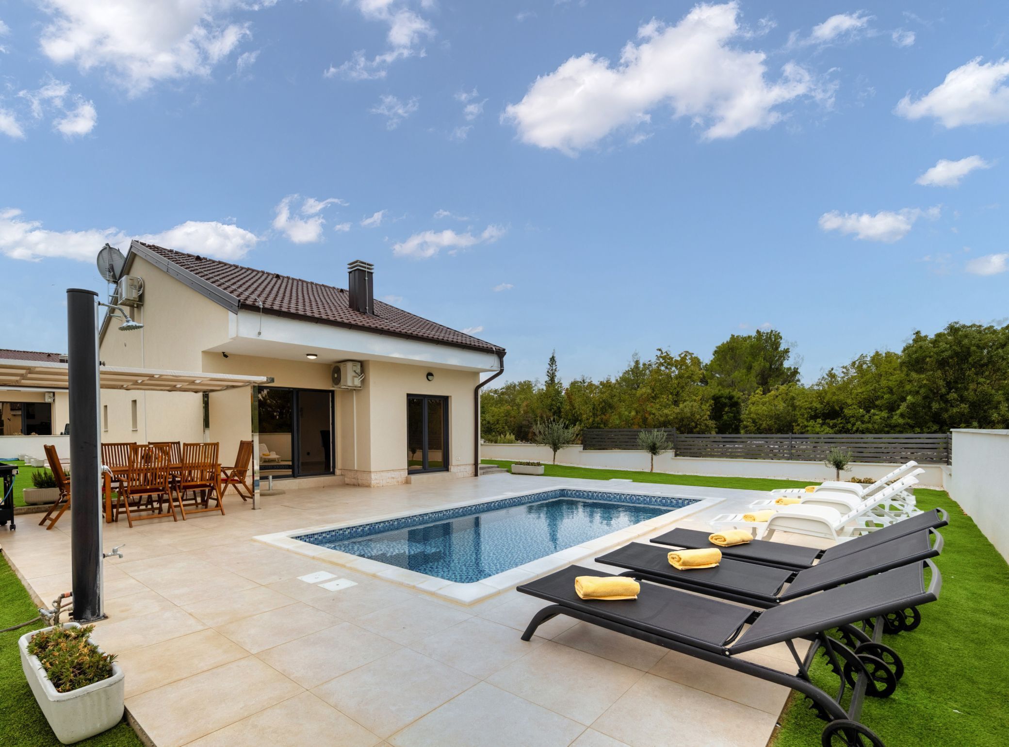 A modern house with a swimming pool, outdoor seating, and a well-maintained lawn.