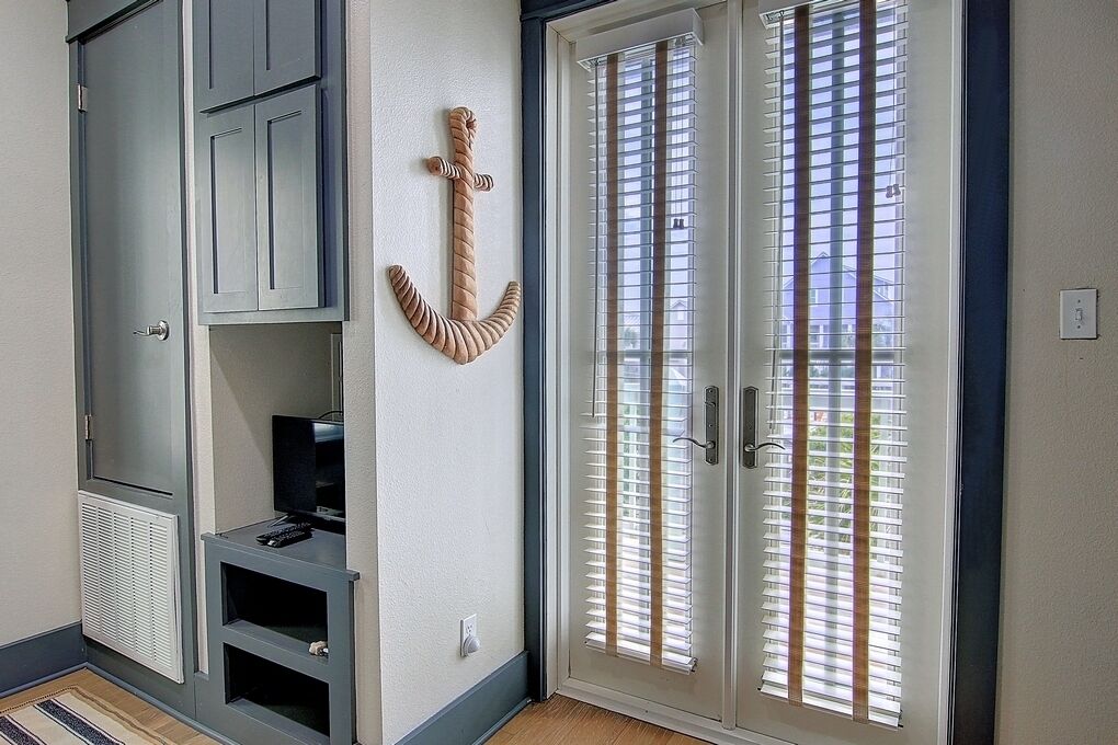 A room with a sliding glass door, a built-in entertainment unit, and a wall-mounted anchor decoration.