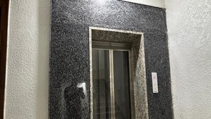 A door with a textured black surface and a glass panel. - Aster Studio Serviced Apartment (Gurugram)