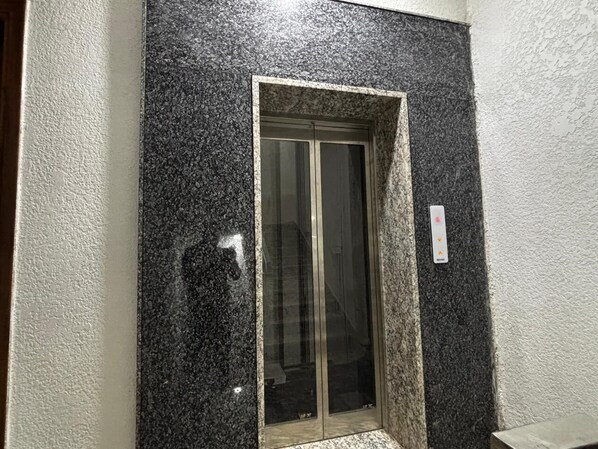 Une porte à la surface noire texturée et dotée d’un panneau de verre.