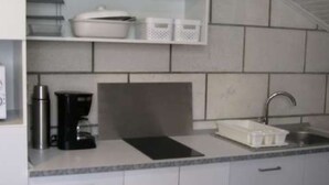 A modern kitchen with grey cabinets, a stainless steel sink, and a coffee maker. - Apartment Jadranka (Lumbarda)
