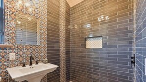 A bathroom with a sink, mirror, and tiled walls.