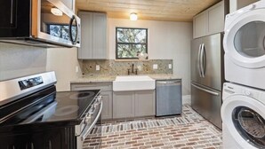 A compact kitchen with a stove, sink, and built-in appliances, including a refrigerator and a dishwasher.