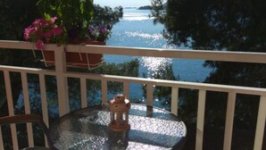 A balcony with a round glass table, a lantern, and a potted plant.
