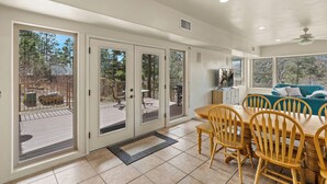 A spacious dining area with a wooden table and chairs, a sliding glass door leading to an outdoor deck, and a ceiling fan.