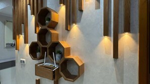 Un interior moderno con paneles de madera en la pared, repisas hexagonales e iluminación empotrada.