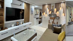 Una sala de estar moderna con un televisor de pantalla plana grande, una mesa de centro y un sofá.