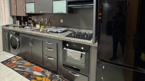 Una cocina moderna con electrodomésticos de acero inoxidable, una encimera de granito y un tapete estampado.