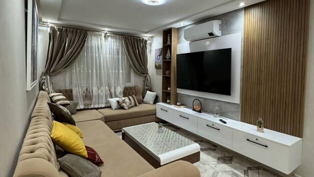 Una sala moderna con sofá, televisor y mueble de entretenimiento.
