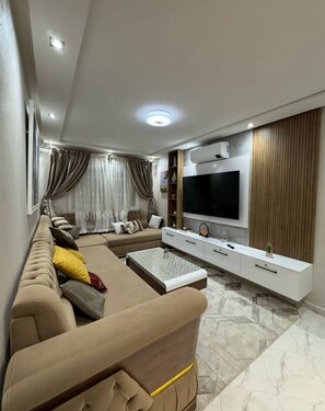 Una sala moderna con sofá, televisor y mueble de entretenimiento.