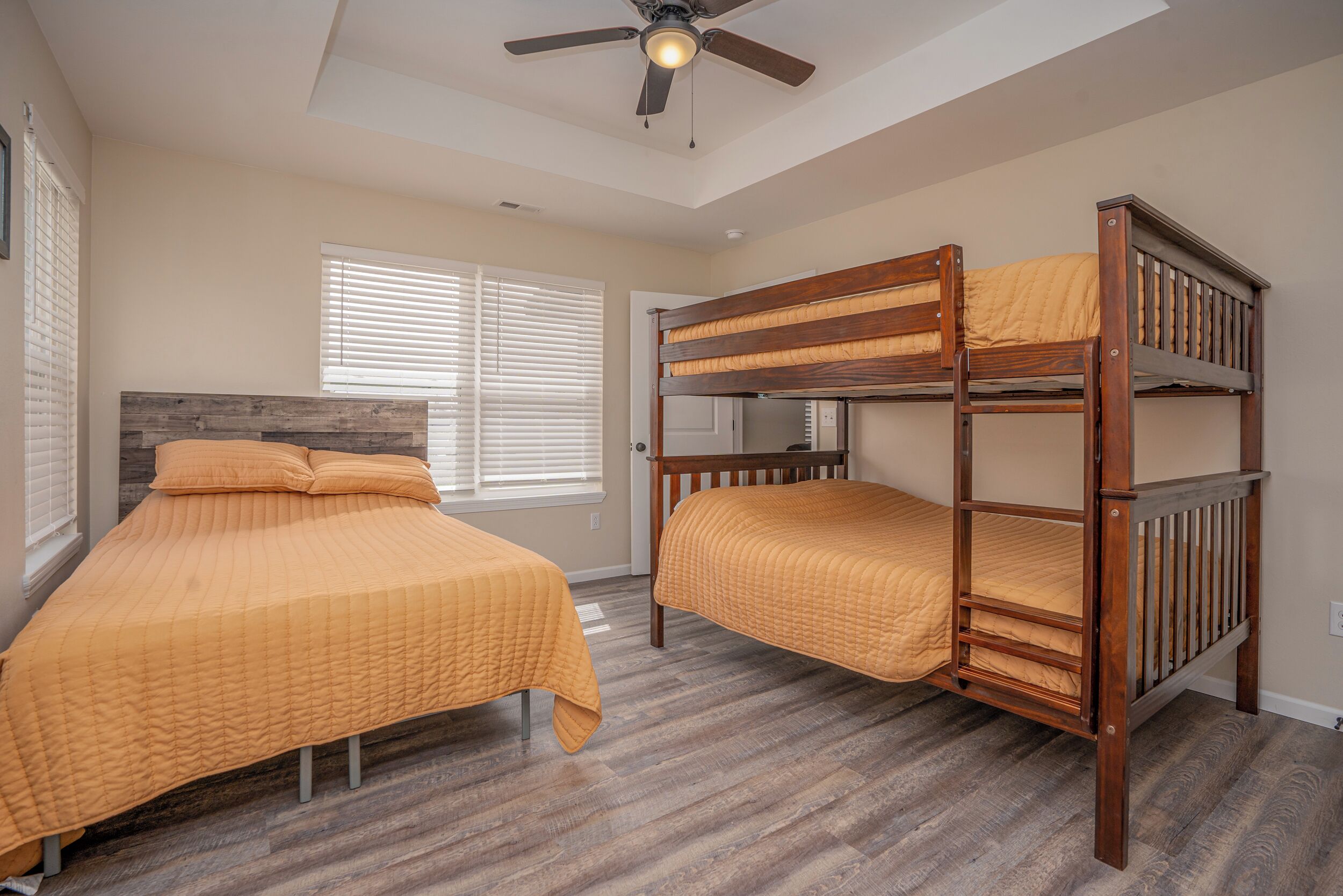 A bedroom with two beds, wooden headboards, and a ceiling fan.