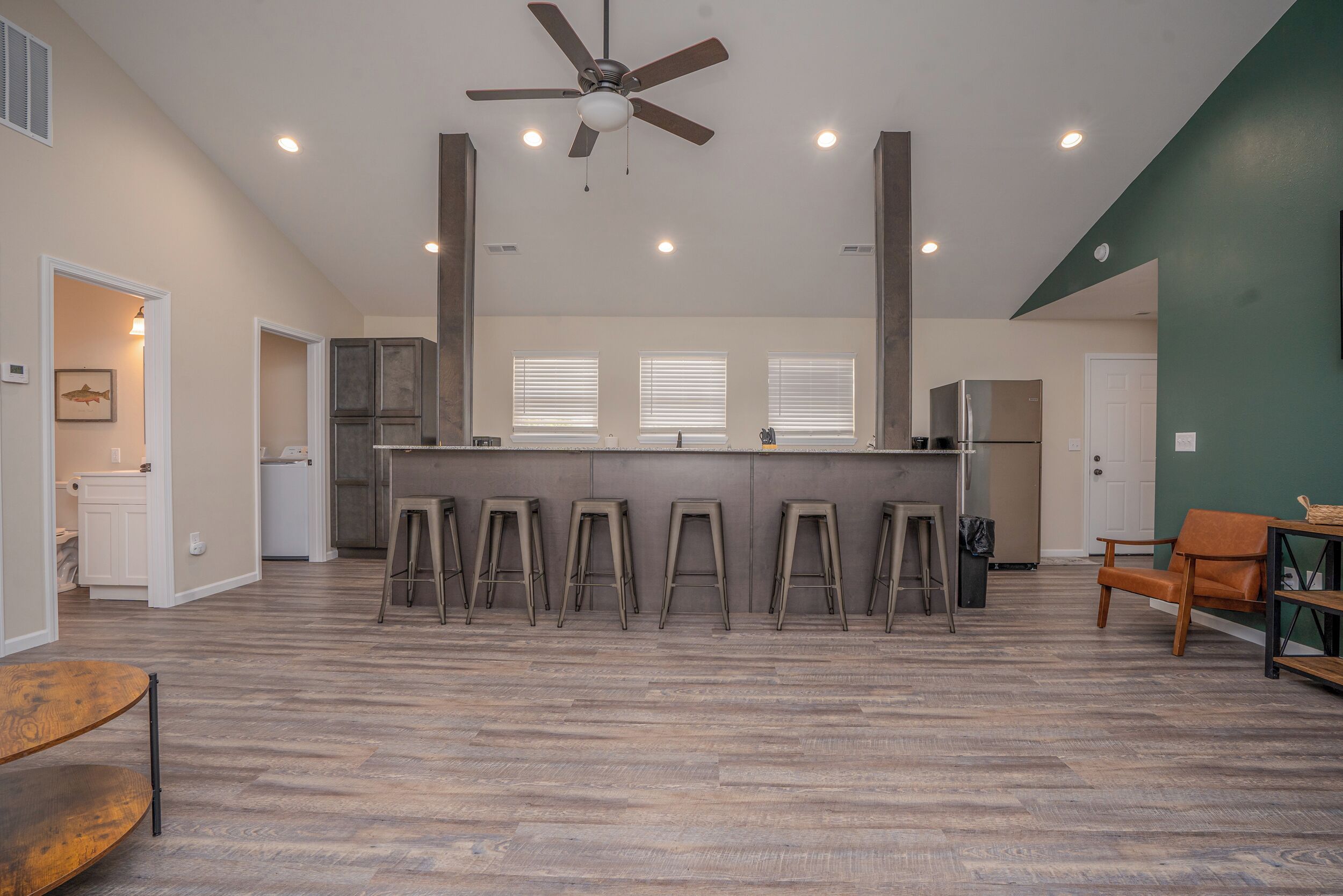 A spacious living area with a central kitchen island, a ceiling fan, and a dining area with stools.