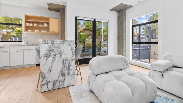 A modern kitchen with white cabinets, a marble island, and a view of a traditional Japanese house through glass doors.