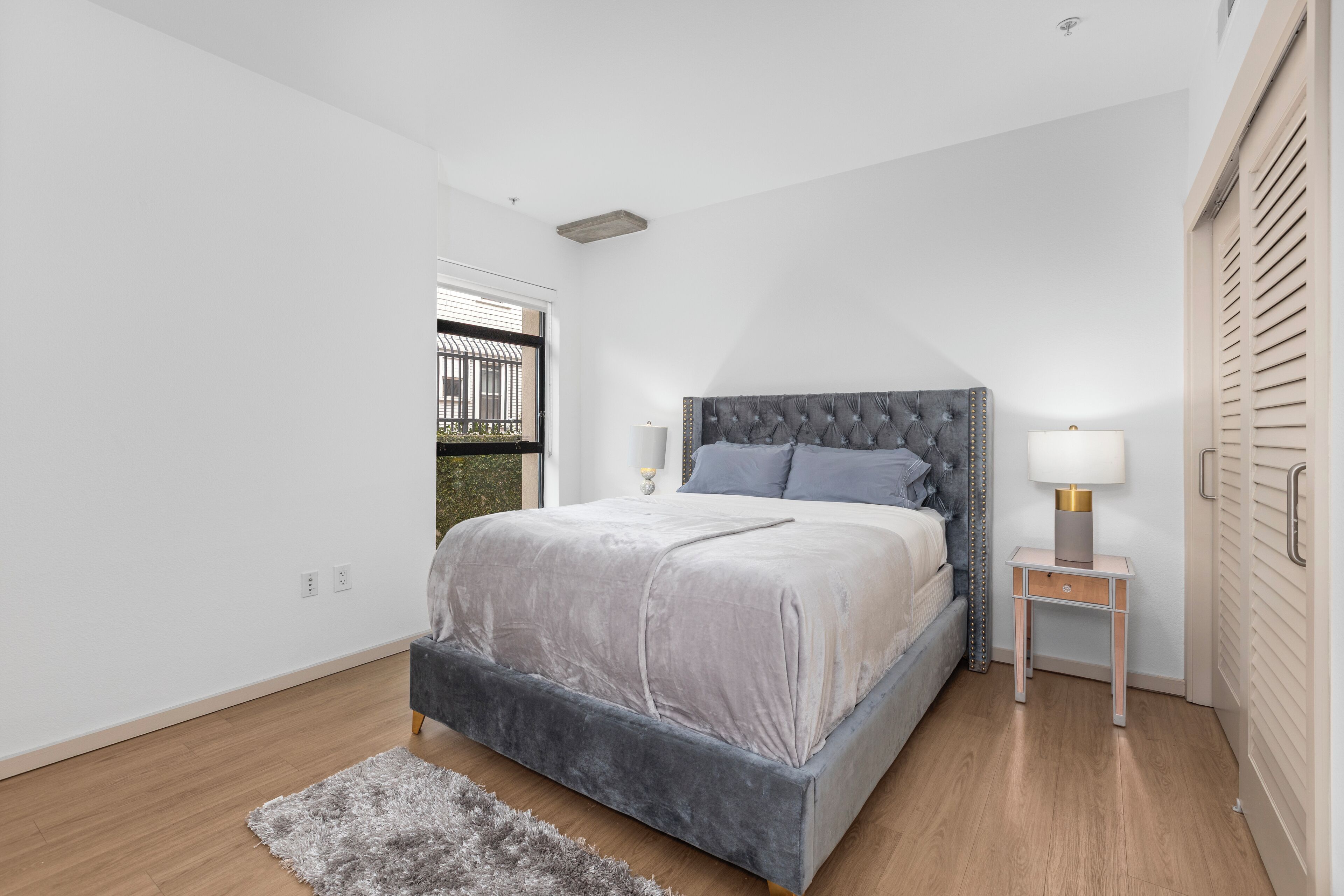 Une chambre à coucher avec un lit, des tables de chevet, une fenêtre et une porte.