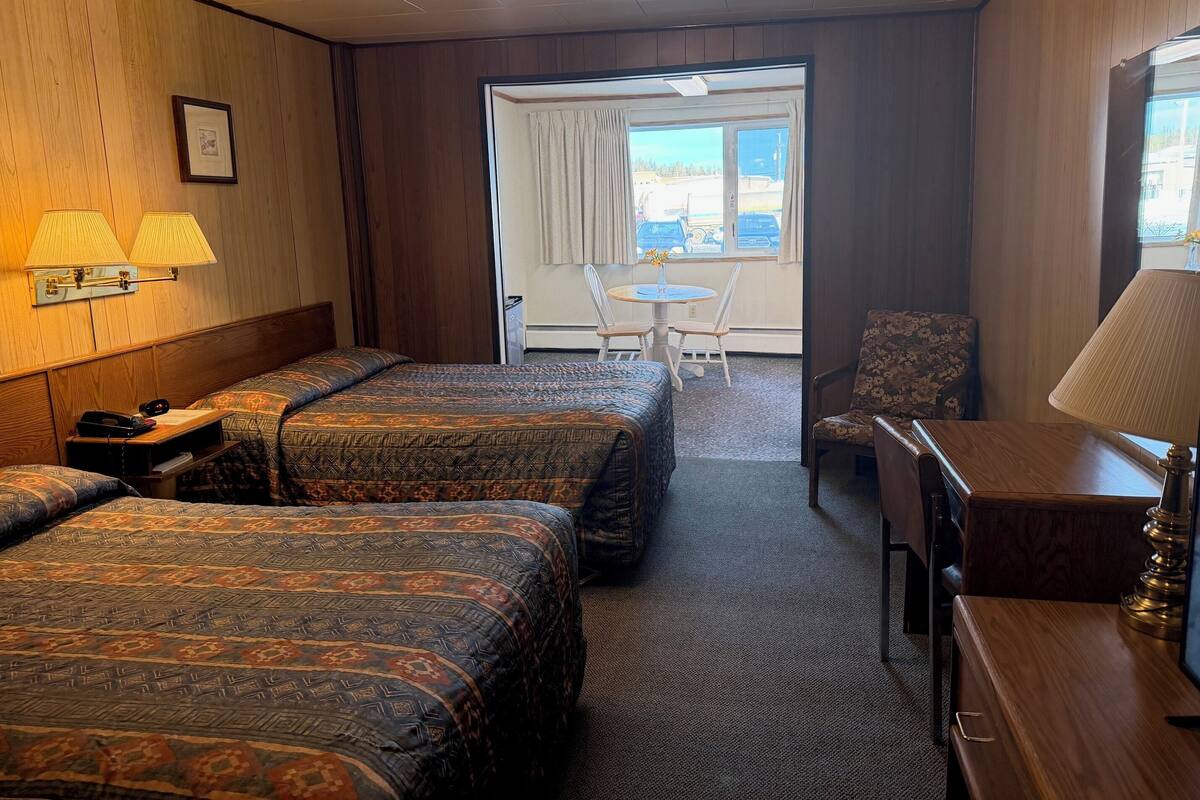 Camera d'albergo con due letti, una scrivania, una sedia e una finestra vista esterna.