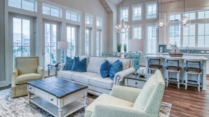 Un salon spacieux avec un plafond haut, de grandes fenêtres et un coin salon confortable avec un canapé et des fauteuils.