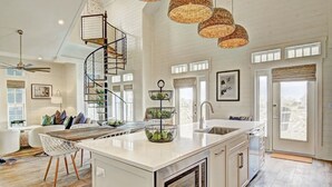 A spacious kitchen with a central island, a spiral staircase, and large windows. - Skytop Lounge TC 5105 (Port Aransas)
