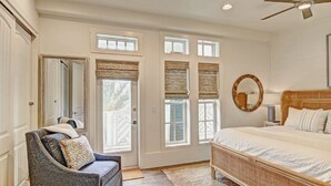 A bedroom with a bed, a chair, a ceiling fan, and windows with blinds. - Skytop Lounge TC 5105 (Port Aransas)