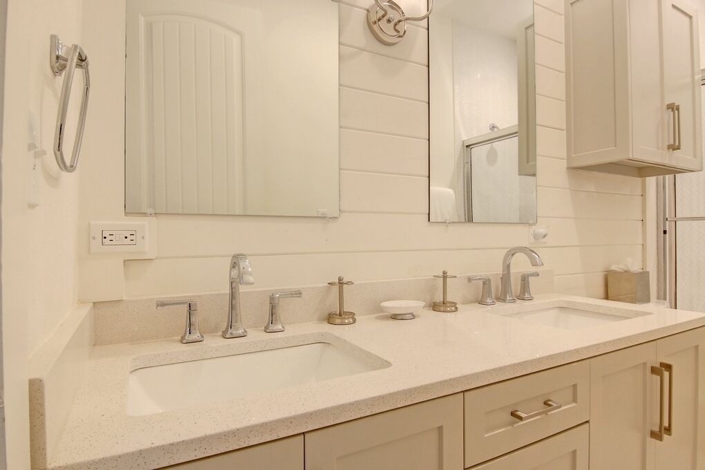 A bathroom with two sinks, a mirror, and a towel rack.
