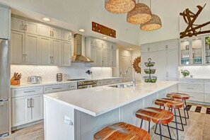 Una cocina moderna con armarios blancos, una isla grande y taburetes de madera.