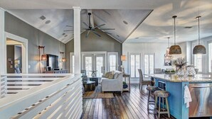 Une cuisine spacieuse avec un plancher en bois, un grand îlot central et un coin bar.