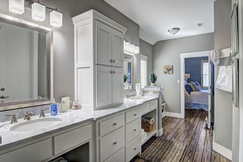 Une salle de bain avec deux lavabos, un grand miroir et un dressing.