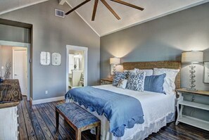Cozy retreat with a large bed, bedside tables, and a bench, set against a neutral gray backdrop.