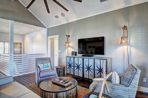 Relax in this stylish living room with a large flat-screen TV, comfortable seating area, and a unique decorative cabinet.