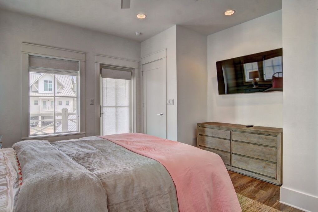 A bedroom with a bed, a dresser, a window, and a painting on the wall.