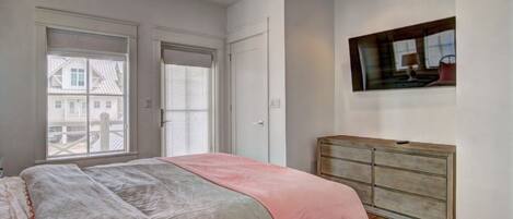A bedroom with a bed, a dresser, a window, and a painting on the wall.