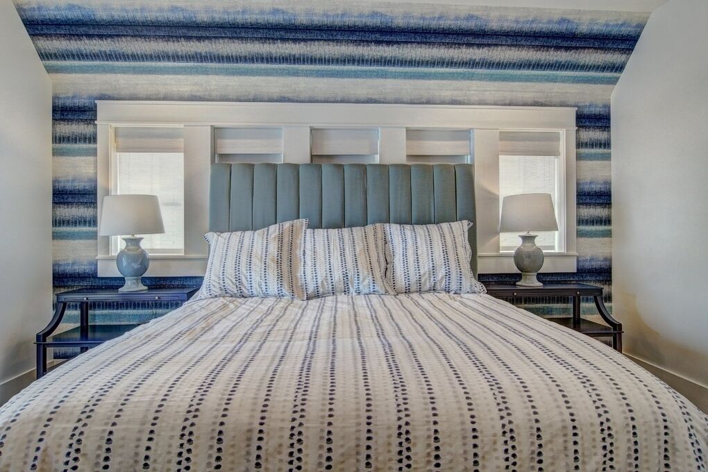 A neatly made bed with a striped bedspread, two bedside tables with lamps, and a headboard with built-in lighting.