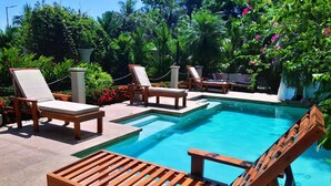 A poolside area with wooden lounge chairs and a rectangular pool. - Villa San Juan a special place in Tela (El Triunfo de La Cruz)