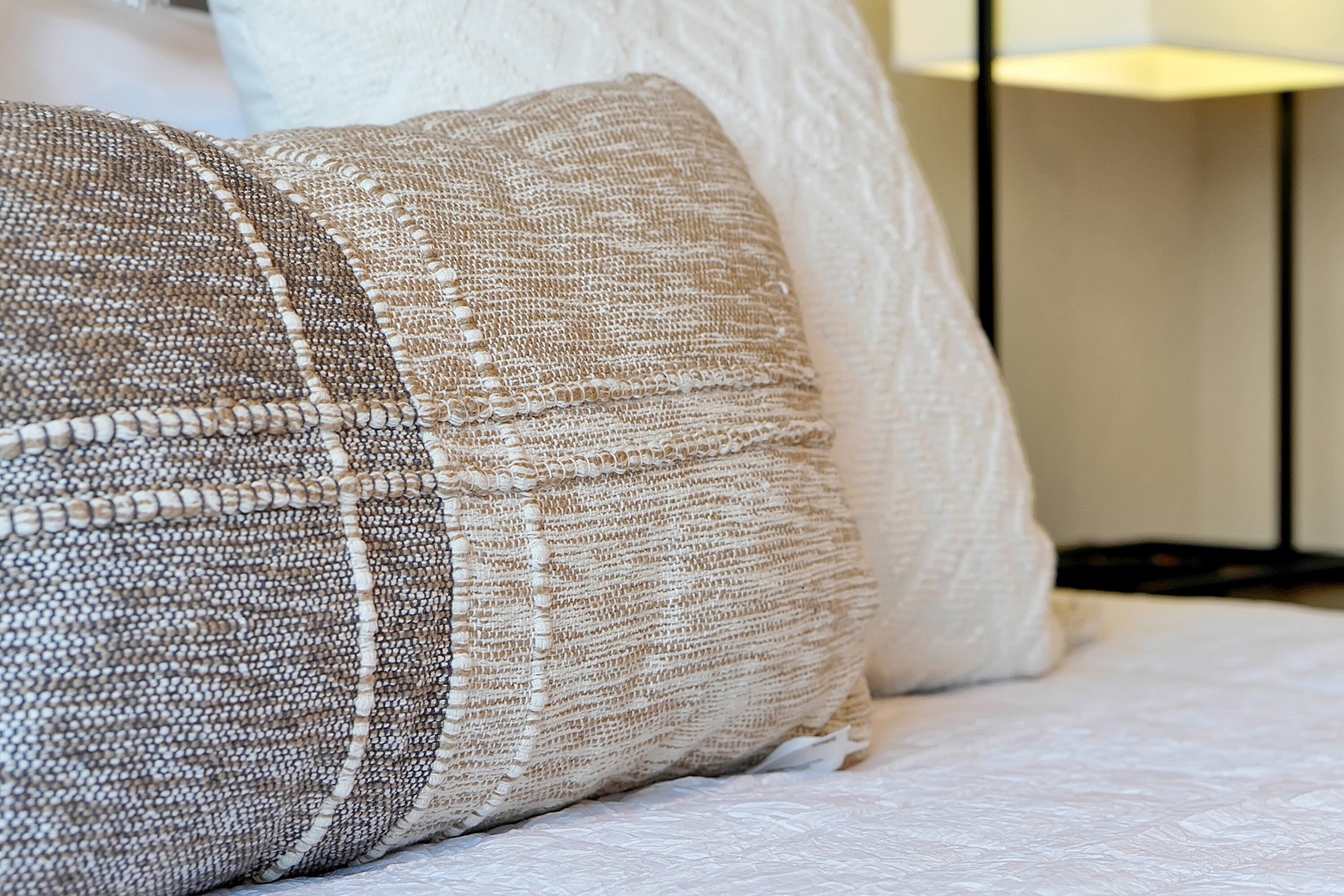 Ein Bett mit zwei gemusterten Kissen und einer weißen Decke.
