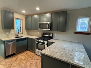 A modern kitchen with dark cabinets, a stainless steel stove, a microwave, and a dishwasher. - Charming 3-bedroom house in Oakmont with AC, WiFi (Oakmont)