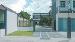 Ein modernes Gebäude mit einem geschlossenem Eingangsbereich, einem überdachten Parkplatz und einem kleinen Rasen.