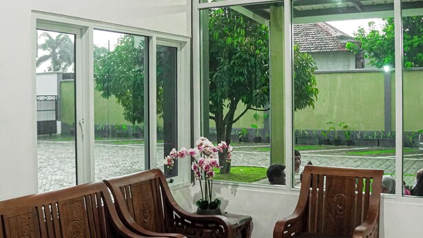 Ein Zimmer mit einer Holzdavonia, einem Glastisch und einem großen Fenster mit Blick auf einen Garten.