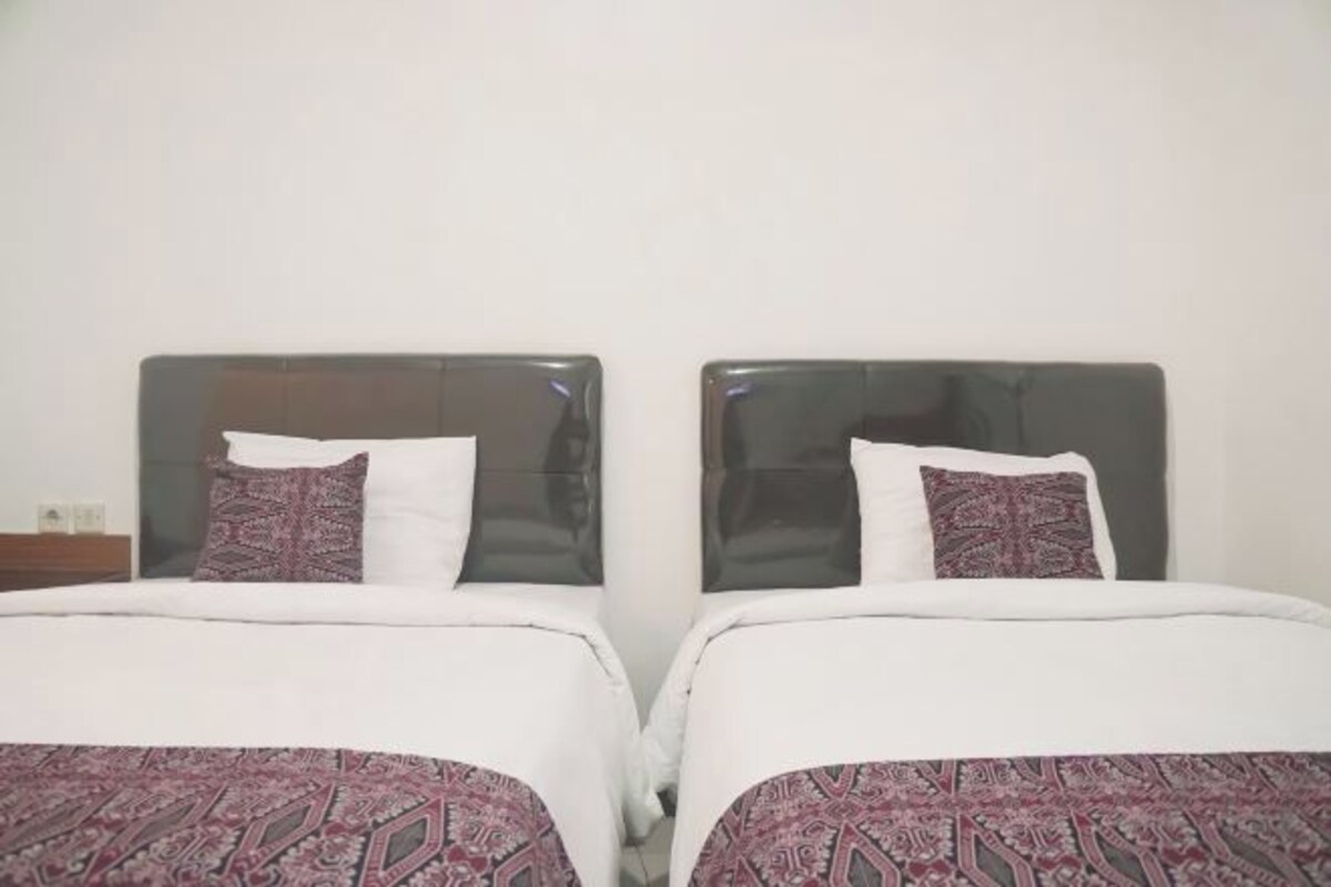 Two twin beds with headboards, white bedding, and patterned throw pillows.