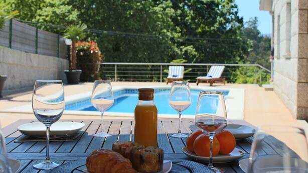 An outdoor dining area with a pool, lounge chairs, and a table set with wine glasses, bread, and fruit. - EXCLUSIVE HOUSE WITH POOL IN GONDOMAR (gondomar)