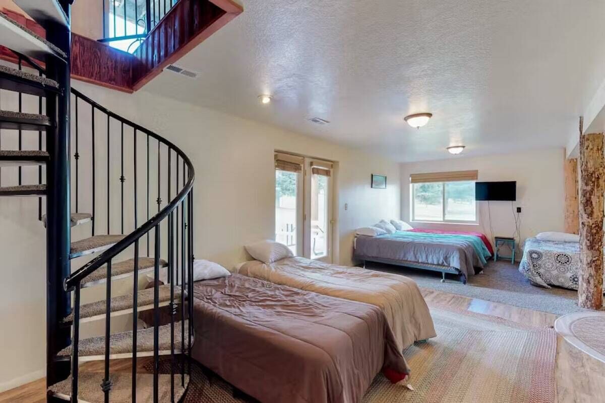 A bedroom with two beds, a staircase, and a large window.