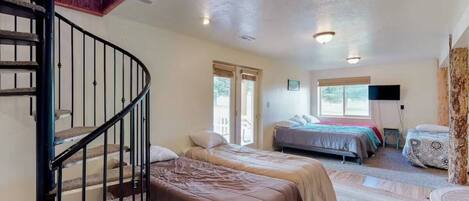 A bedroom with two beds, a staircase, and a large window.