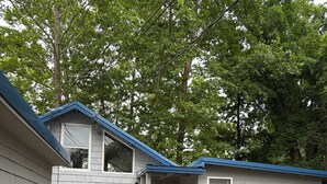 Un piccolo chalet a un piano con una porta blu e un cartello che riporta 'Sunrise Cottage'.