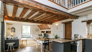 A spacious kitchen with a central island, wooden beams, and a dining area with a sofa and table.