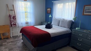 Een slaapkamer met een bed, nachtkastjes, een lamp, een stoel en een raam met gordijnen.