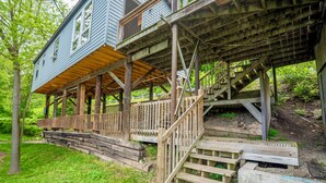 Een huis met een houten terras en een trap naar een balkon op de tweede verdieping.