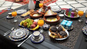 Ein traditioneller marokkanischer Frühstückstisch mit Früchten, Gebäck und Getränken.