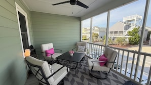 A covered outdoor area with a ceiling fan, a table with chairs, and a view of a residential neighborhood. - Gorgeous Home on Sunset Beach, Just Steps from the Shore! (Sunset Beach)