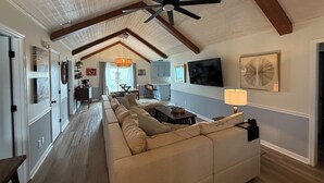 A spacious living area with a high ceiling, a large ceiling fan, and a cozy sofa. - Gorgeous Home on Sunset Beach, Just Steps from the Shore! (Sunset Beach)