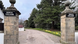 A gravel driveway leading to a building with stone pillars labeled "North College."