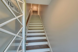 Una escalera con un cartel que dice "The Alpine" y una puerta de vidrio a la izquierda.
